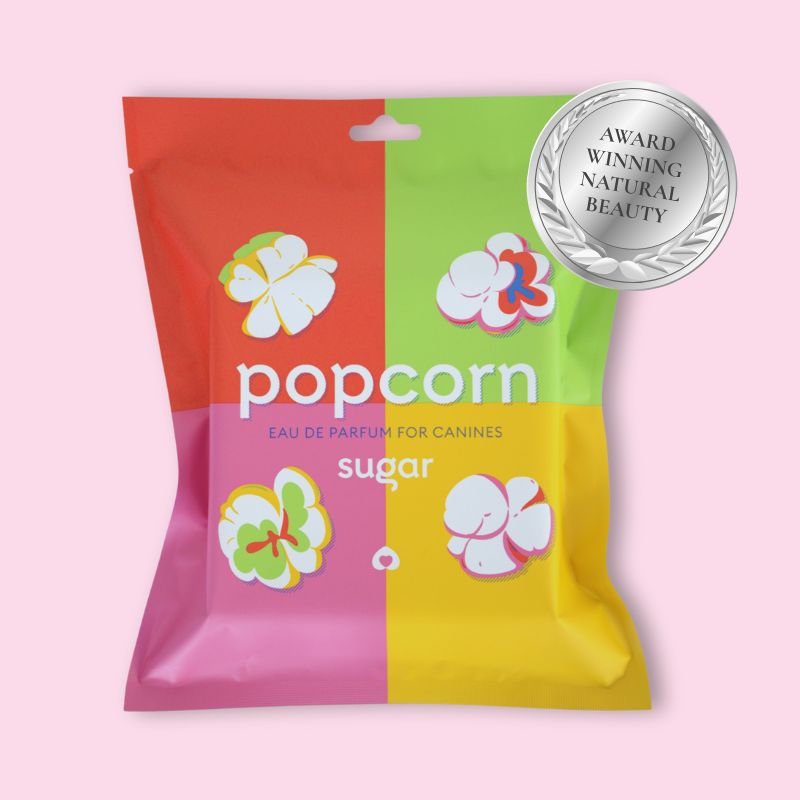 Colorful packaging of Sugar Popcorn dog perfume with silver Natural Beauty Award badge on pink background
